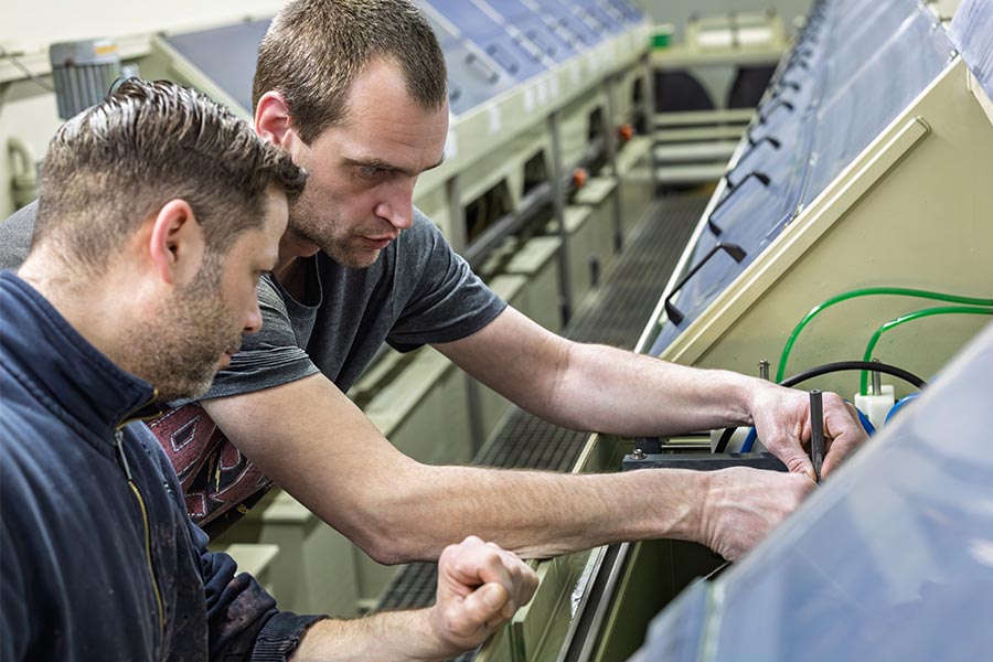 Zwei Mitarbeitende der Deusch & Co. GmbH bei der Einstellung und Kontrolle einer Bandgalvanik-Anlage