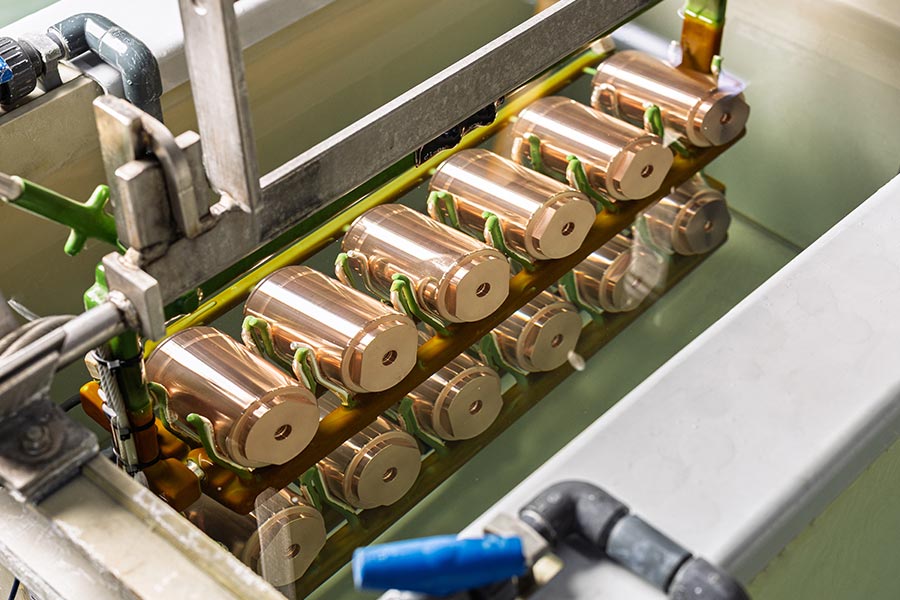 Kupferfarbene zylindrische Bauteile auf einem Gestell im Prozessbad