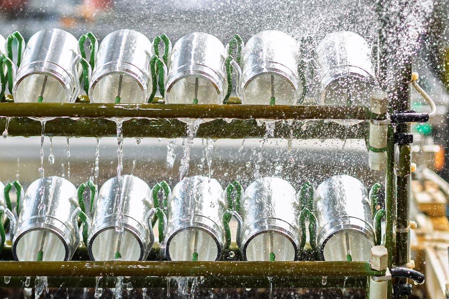 Zylindrische Bauteile auf einem Gestell während des Spülprozesses nach der Oberflächenbehandlung