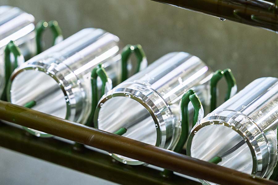 Zylindrische Metallbauteile auf Gestell für die galvanische Oberflächenbehandlung