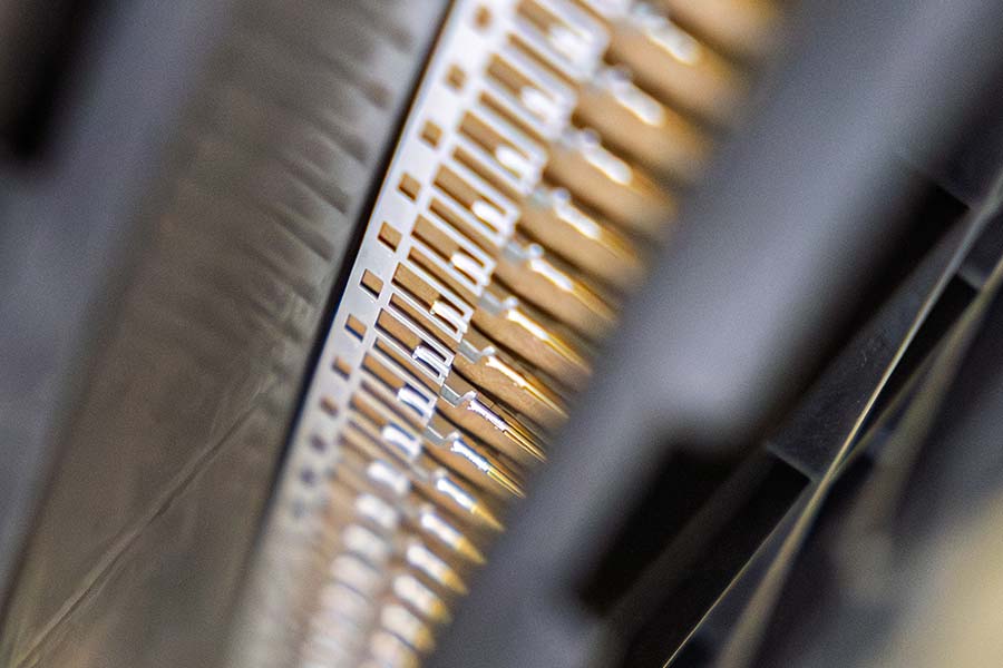 Makroaufnahme von Kontaktteilen auf Bandmaterial in der metallischen Oberflächenveredelung