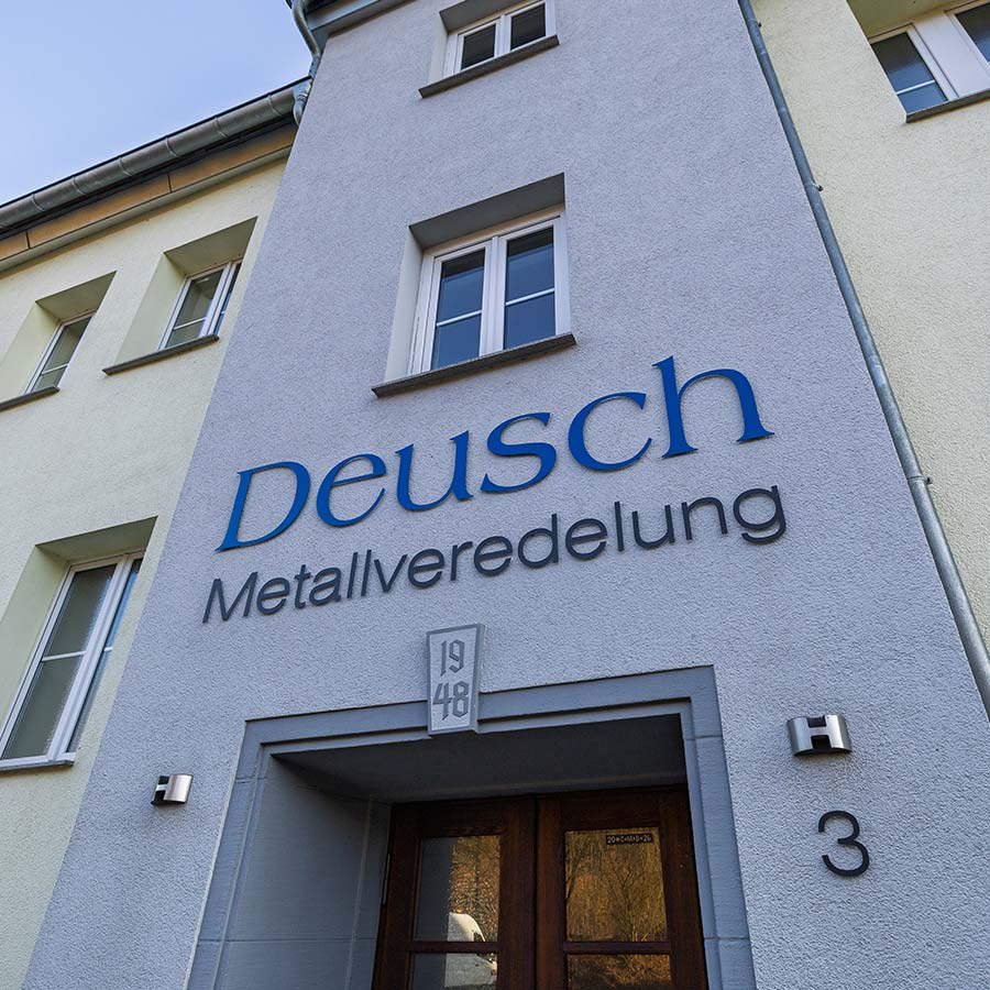 Frontalansicht des Eingangsbereichs am Standort mit Schriftzug „Deusch Metallveredelung“