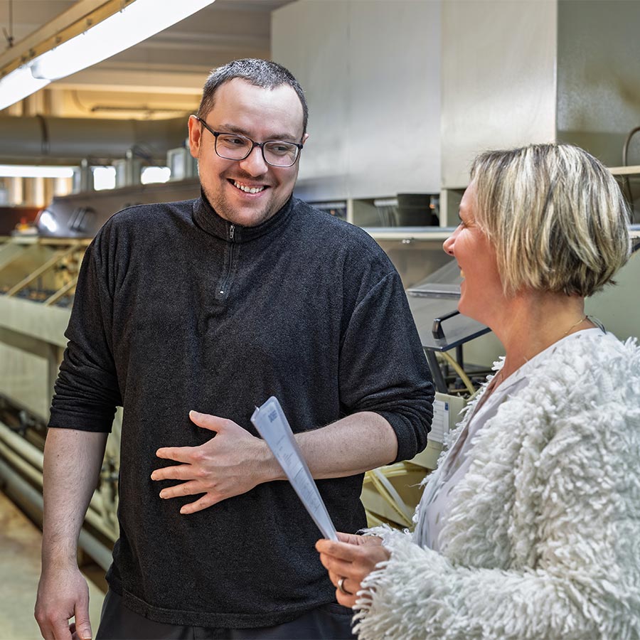 Zwei Mitarbeitende der Deusch & Co. GmbH im Gespräch im Produktionsbereich