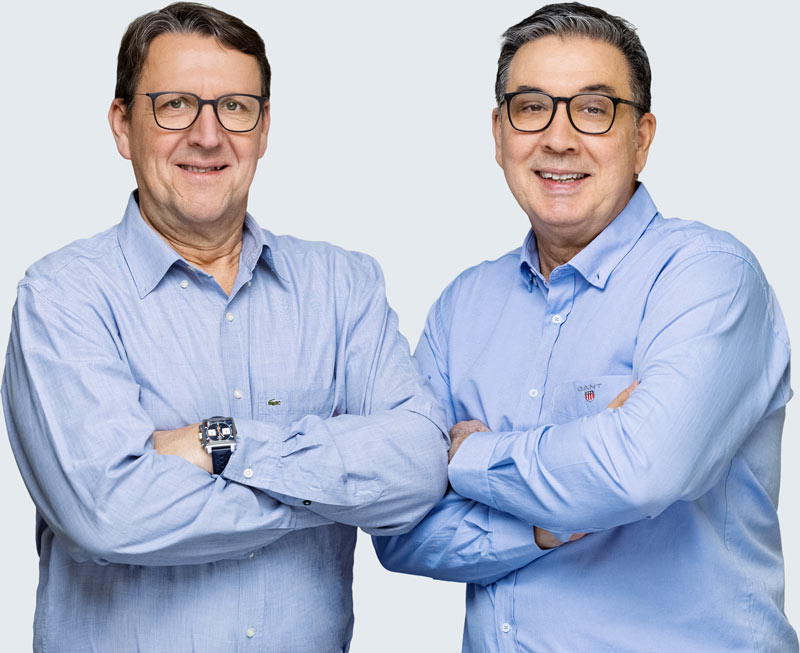 Die zwei Geschäftsführer der Deusch & Co. GmbH im Portrait, mit verschränkten Armen vor hellem Hintergrund